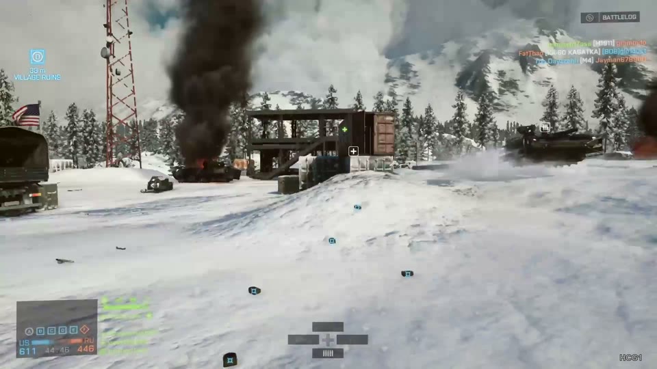 Tank crosses a snowy outpost beside a burning wreck and black smoke, with mountain backdrop and no foreground weapon.