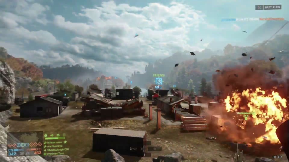 Large orange explosion and scattered debris beside a mountain village, with open sky and no foreground weapon covering the scene.